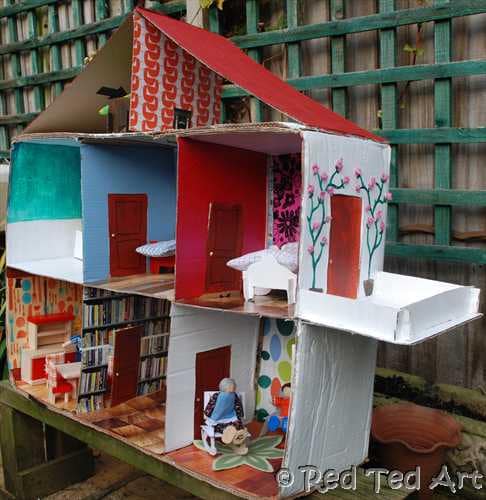 Diy dolls house made from cardboard with a floral balcony, kitchen, bathroom, bedroom, sitting room, and library, and attic.