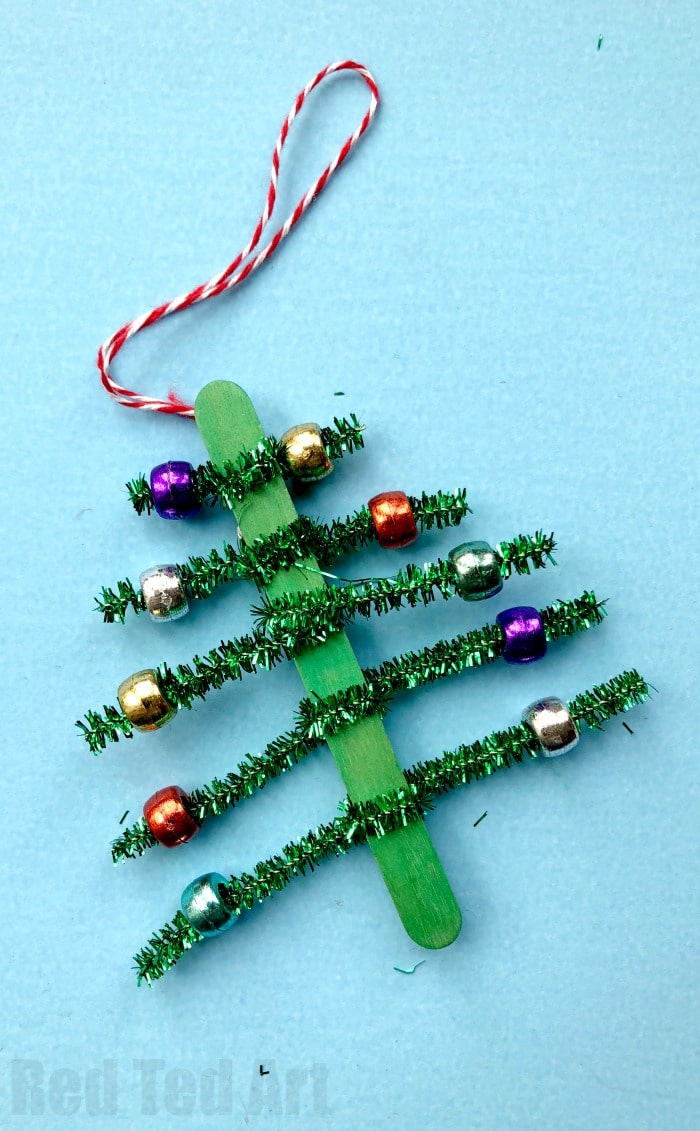 Pipecleaner Christmas Tree Ornaments - super cute and simple craft stick and pipecleaner tree ornaments. The kids will love to make these and they are great for fine motor skills. We made these at the school fair and they went down a treat! #Christmas #Christmastree #preschool #pipecleaner #ornaments
