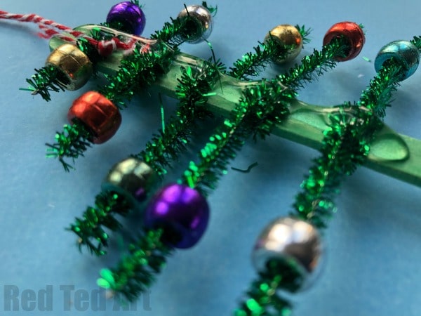 Pipecleaner Christmas Tree Ornaments - super cute and simple craft stick and pipecleaner tree ornaments. The kids will love to make these and they are great for fine motor skills. We made these at the school fair and they went down a treat! #Christmas #Christmastree #preschool #pipecleaner #ornaments