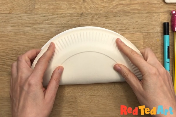 fold the paper plate in half - with the back of the plate on the outside